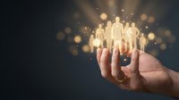 Hand holding glowing human figures with golden bokeh lights representing teamwork, leadership, and human resources management for business concepts.