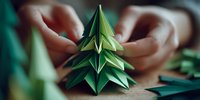 Hands folding green origami paper into decorative Christmas tree shape, showcasing creative holiday craft process on wooden surface.