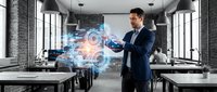 Professional businessman in navy suit interacting with holographic digital interface displaying glowing data visualization in modern office workspace.
