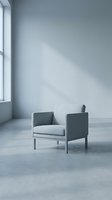 Modern gray upholstered armchair in minimalist interior with concrete floor and natural light from window, suitable for furniture design and contemporary home decor projects.