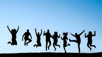 Silhouettes of diverse group of people jumping and celebrating against clear blue sky, expressing joy, freedom, and togetherness for lifestyle and community concepts.
