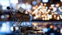 Shopping cart filled with boxes on stack of coins against blurred golden bokeh lights background, reflecting business and retail concept.