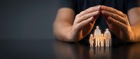 Protective hands covering wooden family figures symbolizing care, security and insurance concept for safety and guardianship in warm lighting.