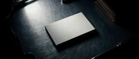 Blank white business card mockup on dark wooden desk with dramatic lighting for corporate branding and identity design projects.