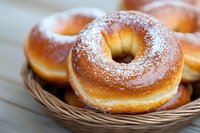 Fresh homemade sugar-dusted donuts with golden brown crust served in woven basket, close up view showing soft texture and powdered coating.