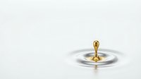 Golden liquid drop splashing and creating ripples on white surface, isolated for design use.