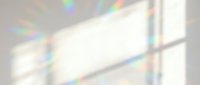 Abstract rainbow light prisms creating colorful spectrum reflections on white surface with geometric shadows and bright luminous effects.