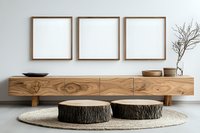 Minimalist living room with wooden floating cabinet, tree stump coffee tables on round jute rug, and three empty square frames on white wall. Natural decor setting.