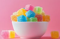 Colorful sugar-coated jelly candies in white bowl on pink background. Sweet gummy treats for confectionery, dessert and candy shop marketing materials.