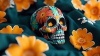 Mexican folk art skull decorated with bright floral patterns surrounded by orange marigold flowers on dark teal background, celebrating Day of Dead traditions.