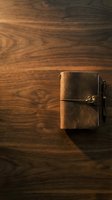 Vintage brown leather journal with metal pen resting on rich wooden surface, ideal for writing, planning, journaling, and creative projects.