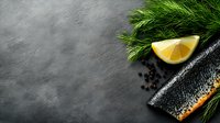 Lemon slice with fresh dill herbs and peppercorns on dark slate surface. Culinary styling for food photography, recipe blogs, restaurant menus, cooking websites.