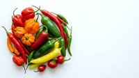 Fresh assorted peppers including red, yellow, orange and green varieties with cherry tomatoes arranged on white background for culinary and food styling use.
