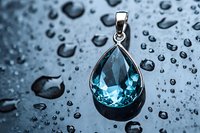 Elegant teardrop aquamarine pendant on wet surface with water drops background. Luxury jewelry photography showcasing gemstone brilliance and clarity in blue tones.