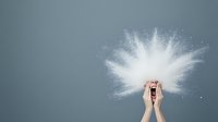 Hands cupping and releasing white powder explosion against gray background, creating dramatic cloud effect for cosmetic and creative commercial photography.