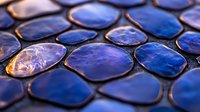 Blue iridescent mosaic tiles with metallic edges creating geometric pattern for interior design and decorative applications in modern architecture.