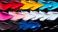 Vibrant arrow shapes created with thick paint strokes in multiple colors against dark background, showing texture and movement in modern abstract composition.
