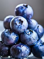 Fresh ripe blueberries with water drops in macro shot, showing natural bloom coating and juicy texture on dark background for healthy eating concept.