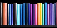 Colorful book spines arranged in rainbow order on black background create vibrant library pattern, suitable for education and learning concepts.