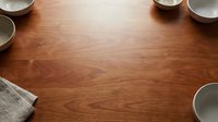 Young woman with medium skin tone, wearing casual attire, preparing ingredients in a bright kitchen workspace. Overhead flat lay composition featuring wooden table surface with bowls and linens, ideal for food blogging, recipe content, and culinary design projects.