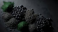 Black beans, lentils and green powder arranged on dark slate surface for healthy cooking and nutrition concepts.