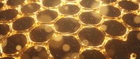 Golden honeycomb structure with glowing hexagonal cells and bokeh particles, suitable for backgrounds, technology concepts, and abstract design projects.