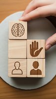 Wooden blocks with human resources icons including brain, hand, and people symbols arranged by hands on plate representing HR management concepts.