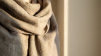 Beige wool shawl draped elegantly with soft folds and natural texture, suitable for fashion, lifestyle, and textile design projects.