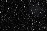 Water drops on dark glass surface create dramatic pattern of scattered raindrops with light reflections. Natural condensation background for atmospheric designs.
