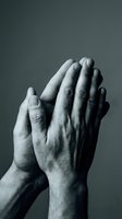 Elderly hands pressed together in prayer position showing wrinkled skin and age spots in dramatic black and white photography for spiritual and religious concepts.