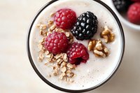 Healthy breakfast smoothie bowl topped with fresh raspberries, blackberry, granola and nuts for nutritious morning meal and wellness lifestyle.