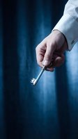 Businessman in white shirt holding silver key against blue background, symbolizing success, opportunity, and unlocking potential for business solutions.