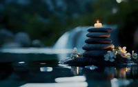 Balanced zen stones with glowing candle on top near water surface, white flowers and soft bokeh lights creating peaceful spa atmosphere at dusk.