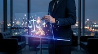 Professional businessman holding digital tablet with glowing justice scales hologram in modern office at night representing legal technology solutions.