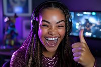 Young African American woman with braids showing excitement while wearing headphones and sequined top, expressing joy with thumbs up in purple neon-lit gaming environment.