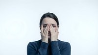 Young Asian woman covering face with hands showing embarrassment shame or stress wearing dark sweater on white background isolated for design use.