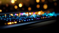 Colorful illuminated gaming keyboard with RGB backlight glowing in dark room against blurred bokeh background, creating atmospheric gaming setup mood.