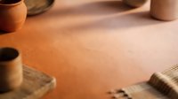 Young adult female of mixed ethnicity working on leather crafting project, cutting and shaping tan leather material with tools for handmade goods production.
