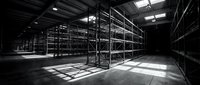 Empty industrial warehouse interior with metal shelving systems and dramatic lighting for logistics and storage concepts.