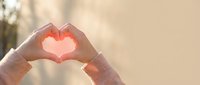 Hands forming heart shape with warm sunlight shining through, expressing love and affection for Valentine's Day, romance, and relationship concepts.