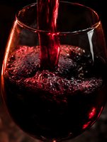 Red wine pouring into glass with bubbles and splash against dark background for luxury dining and celebration concepts.