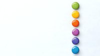 Colorful round candies or buttons arranged vertically in rainbow order on white background, isolated composition for creative design and marketing materials.