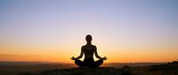 Person meditating in lotus pose silhouetted against stunning sunset sky, peaceful mindfulness practice for wellness and spiritual growth concepts.