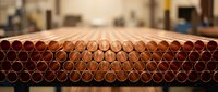 Stack of copper pipes arranged in rows at construction site or warehouse ready for plumbing installation and building projects.
