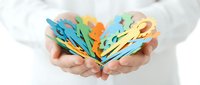 Hands holding colorful paper cut butterflies in rainbow colors, symbolizing transformation, creativity and hope for environmental conservation projects.