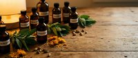 Natural essential oil bottles with herbs and spices on rustic wooden background for aromatherapy wellness spa treatment and holistic healing remedies.