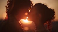 Romantic couple silhouette kissing at golden sunset with warm sunlight creating intimate backlit scene for love and relationship concepts.