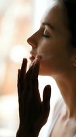 Young woman with closed eyes touching face in warm sunlight expressing serenity and mindfulness in peaceful morning moment for wellness and self-care concepts.