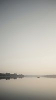 Serene lake at dawn with lone boat and misty atmosphere creating peaceful morning landscape for meditation and wellness content.