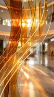 Twisted amber and golden translucent ribbons with flowing curves create an abstract light installation in a modern interior space, suitable for contemporary design projects.